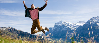 Ein Mann in bayrischer Tracht springt vor Bergkulisse (Bild:  colourbox.com)